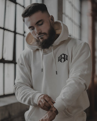 young male model wearing a RENOWNED WEAR Cream Logo Hoodie. looking great 